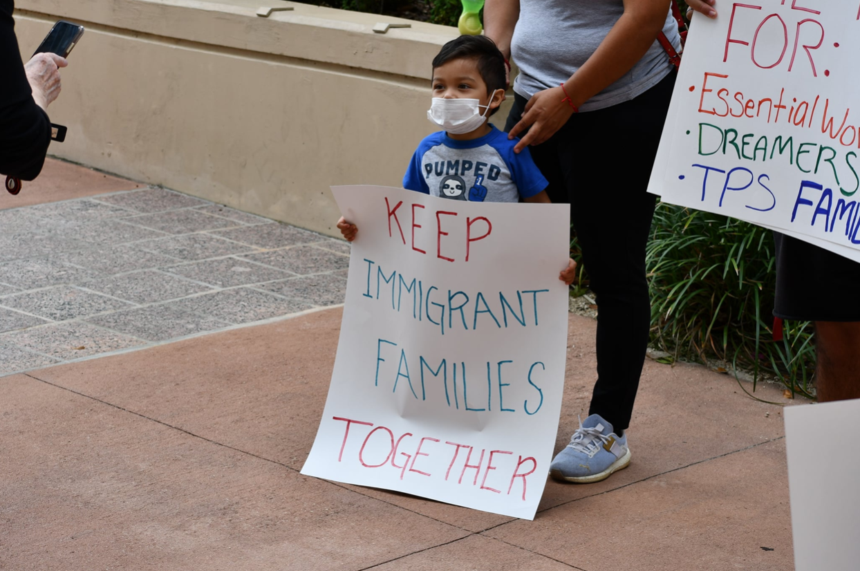 A young Latino boy holds a handmade sign that reads: "Keep Immigrant Families Together."